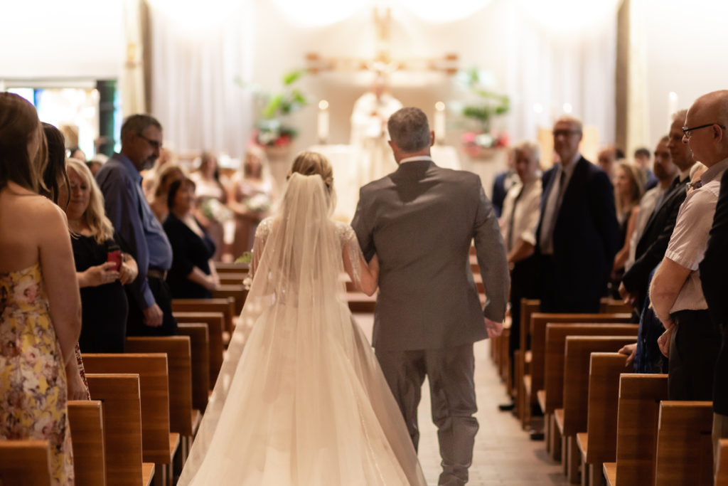 Bride walking down the aisle of Holy Name Catholic Church in Wayzata Minnesota with her father. 