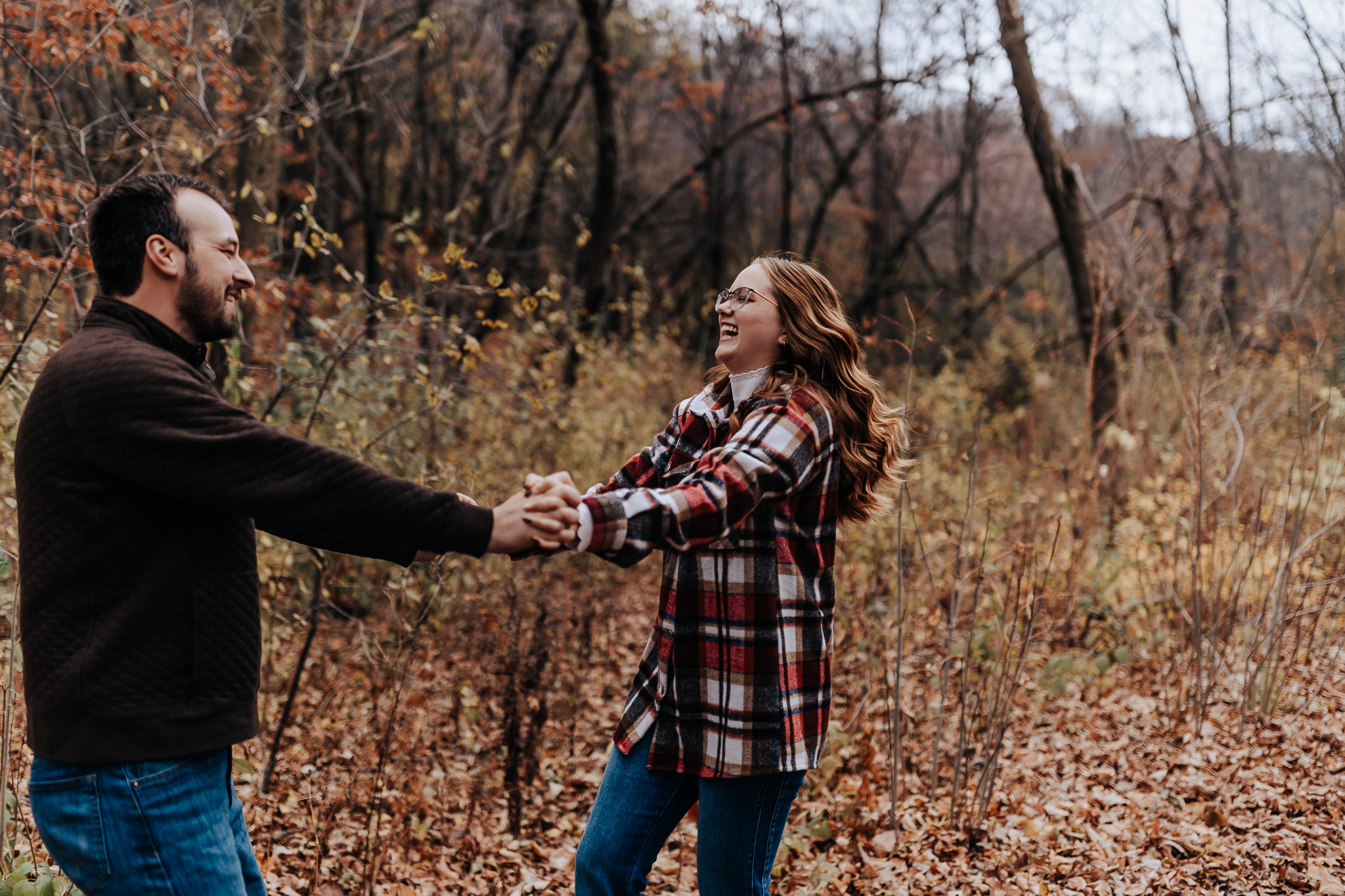 A joyful spin surrounded by fall foliage—layered flannel and fleece make this one of the coziest engagement outfit ideas for couples.
