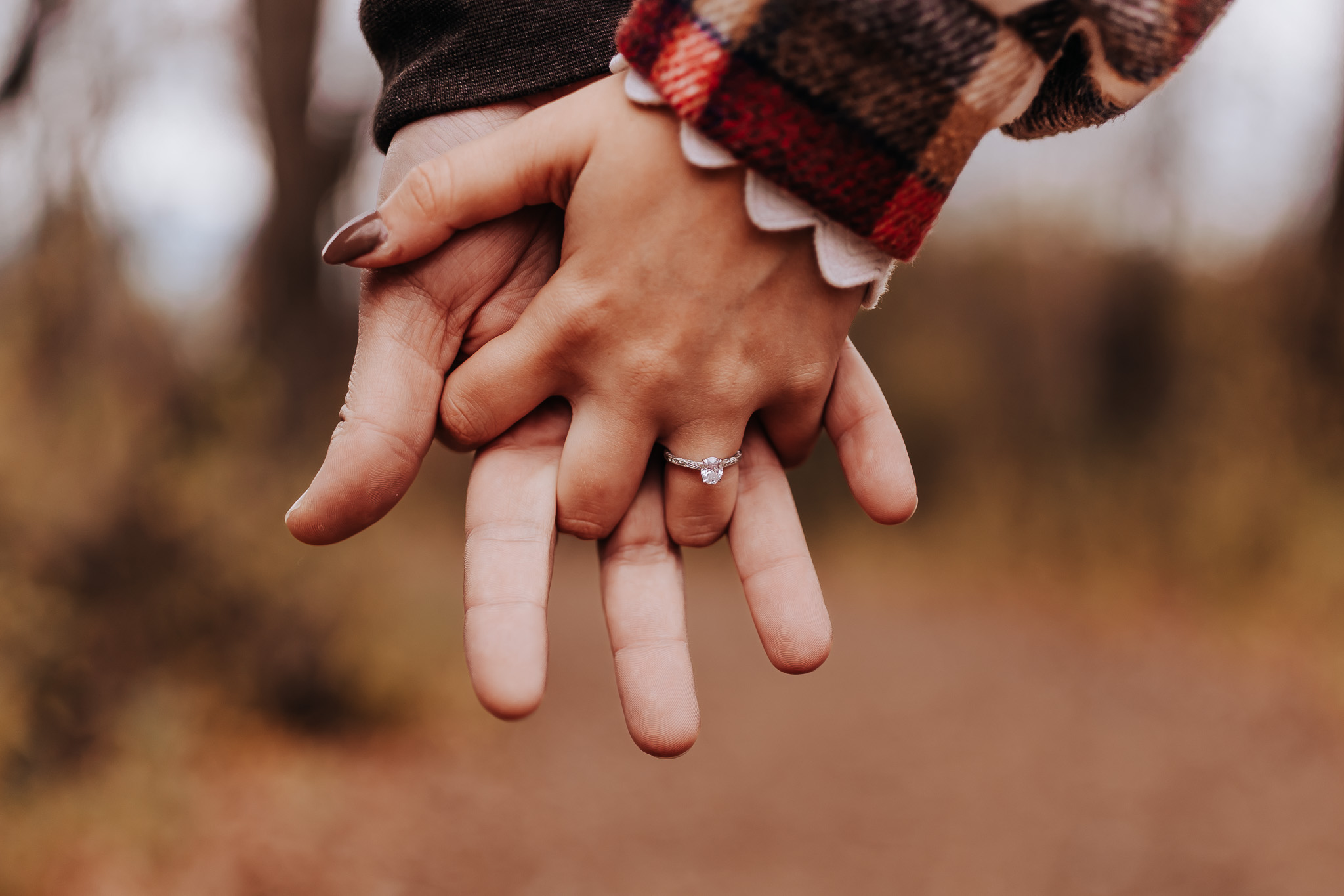A straight couple holding hands. The shot is entirely of their hands and the focus is on the diamond engagement ring on the females left hand. Minnesota Engagement Photographer
