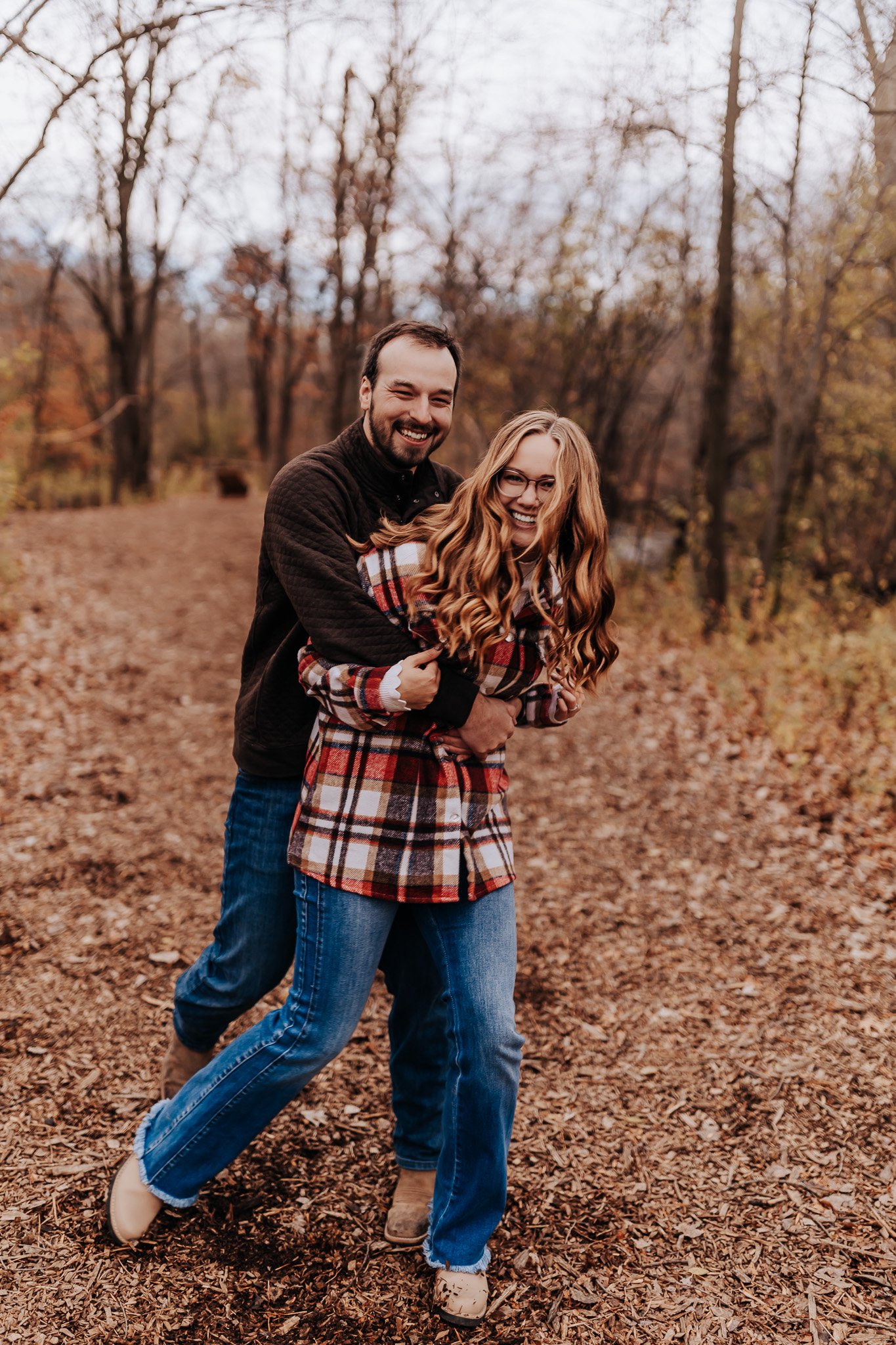 A playful moment captured mid-stride, showing off relaxed and coordinated denim and flannel—great inspiration for engagement outfit ideas for couples.