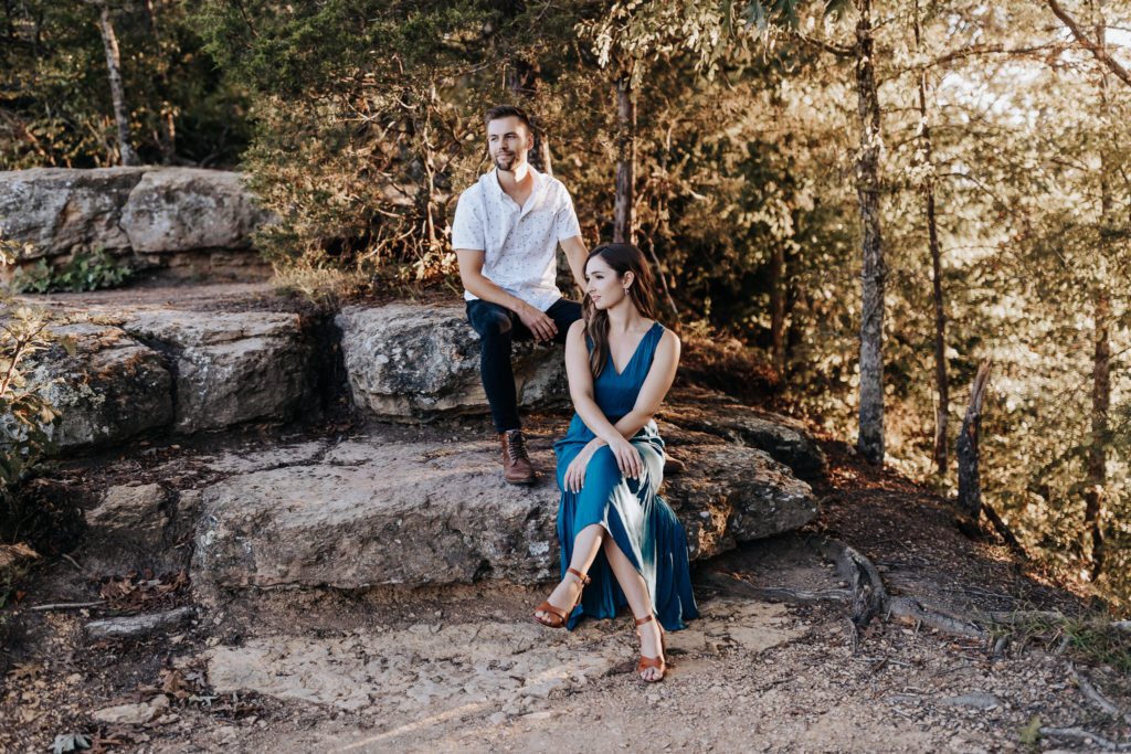 engagement photo of a couple sitting on rocks. they are looking away from the camera. fall engagement session in nashville