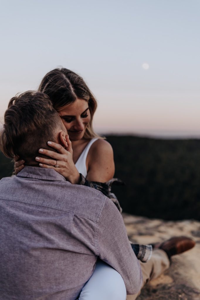 A couple hugging each other and you can see the moon in the background. Tennessee Sunset Mountain Engagement