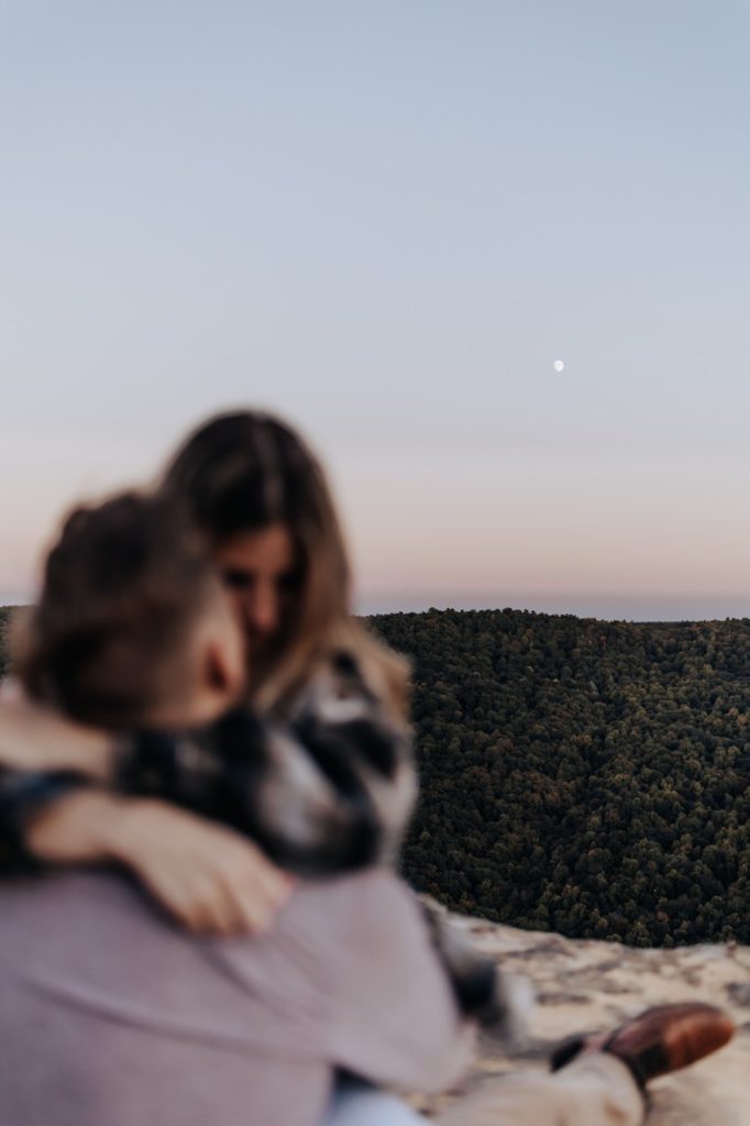 A couple hugging each other and you can see the moon in the background. Tennessee Sunset Mountain Engagement