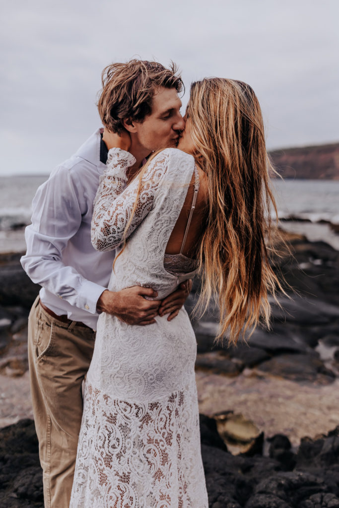 Destination Wedding Photographer captures bride and groom kissing on beach after Hawaii elopement