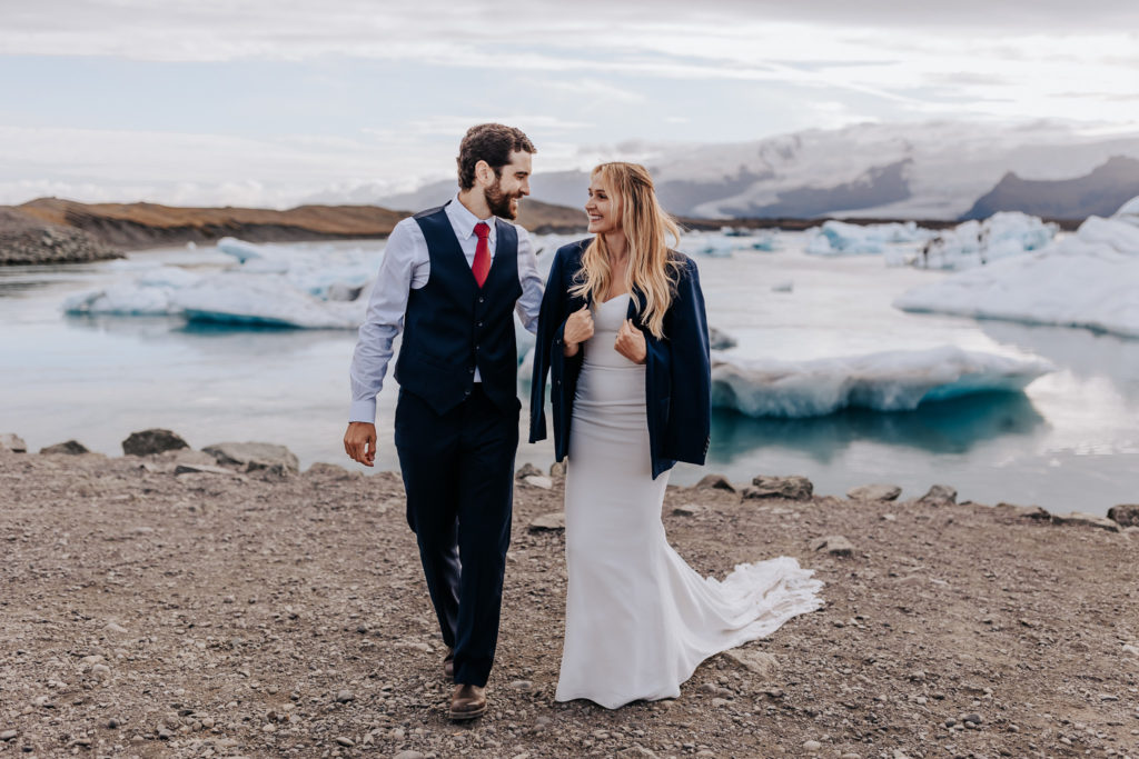 Iceland elopement photographer captures bride and groom walking on sandy beach in Iceland