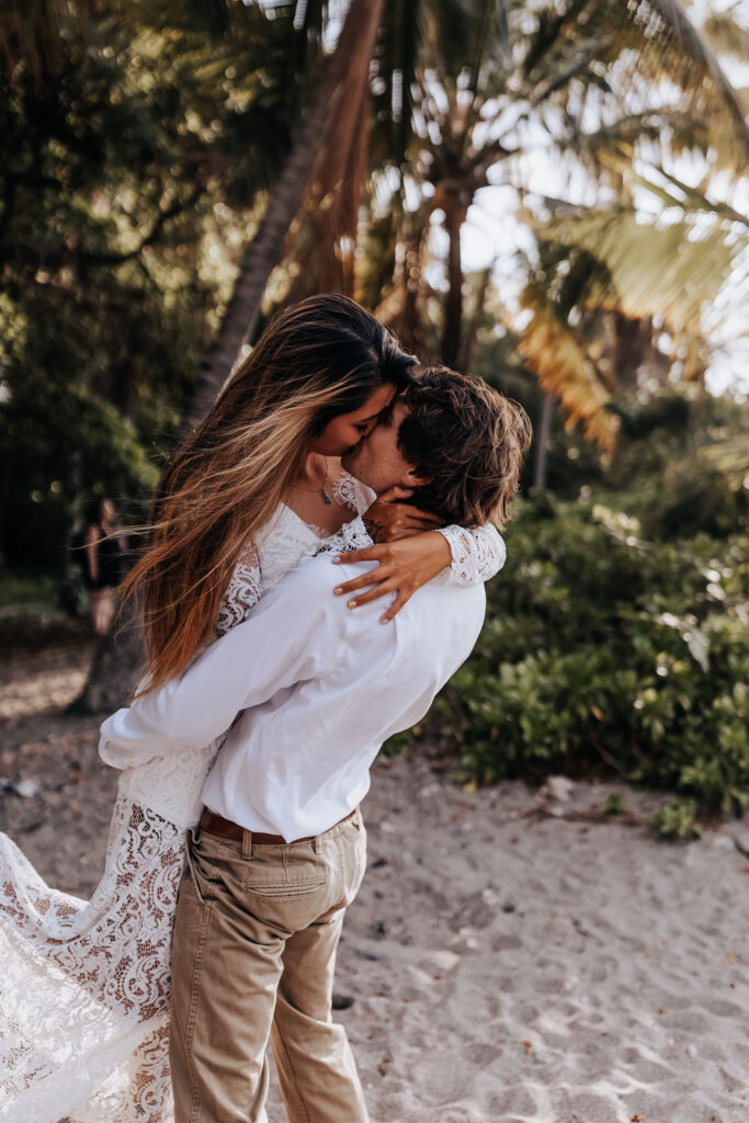 Big Island elopement photographer captures man lifting woman up and kissing her after elopement