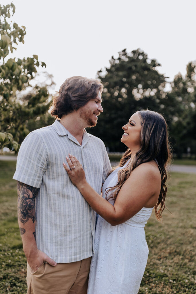Nashville elopement photographer captures couple looking at one another wearing white outfits during summer engagement photos