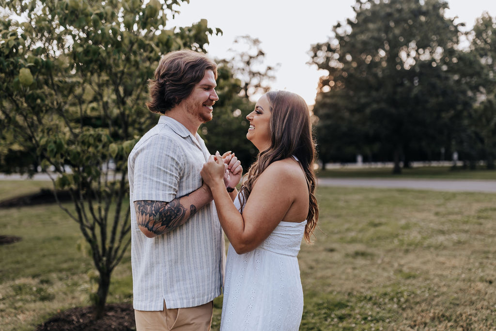 Nashville elopement photographer captures couple holding hands and looking at one another during summer engagement photos