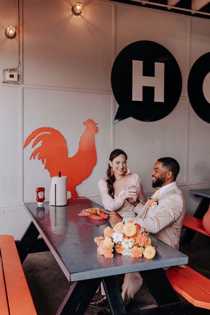Nashville elopement photographer captures couple sitting together at Hattie B's after intimate retro elopement ceremony