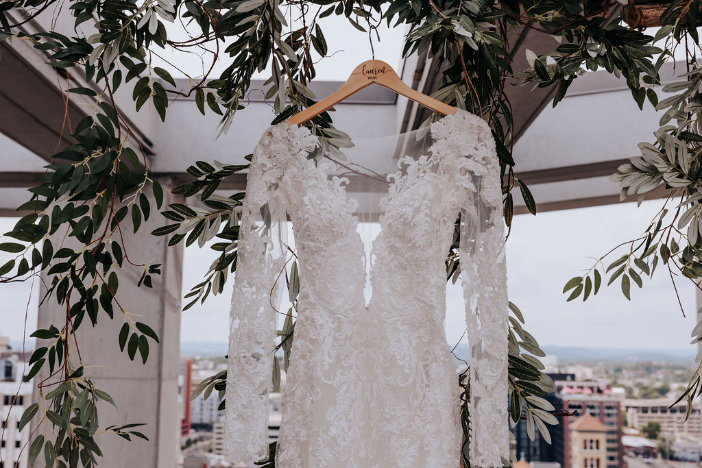 Nashville elopement photographer captures wedding gown hanging from pergola with leaves surrounding