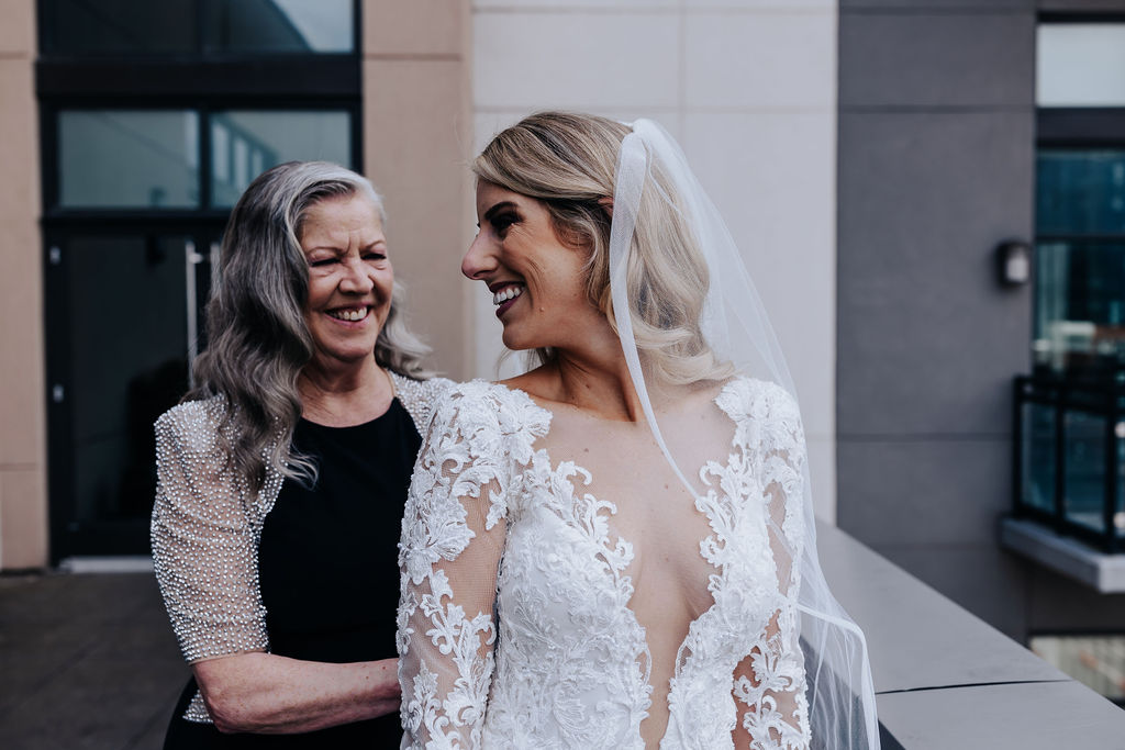 bride being buttoned into dress by mother