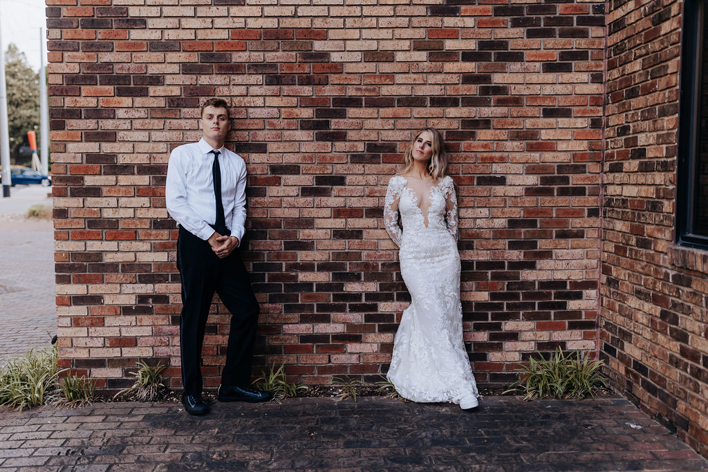 Nashville elopement photographer captures couple standing against brick wall during bridal portraits