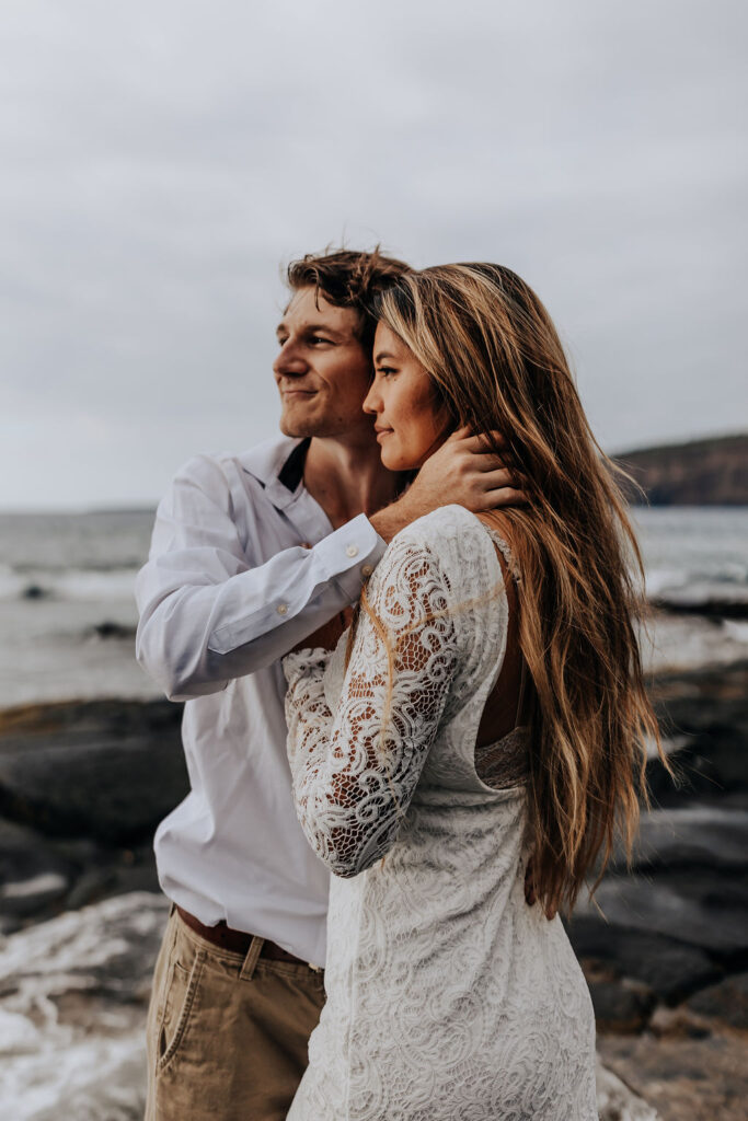 Big Island elopement photographer captures groom holding bride's neck and watching sunset