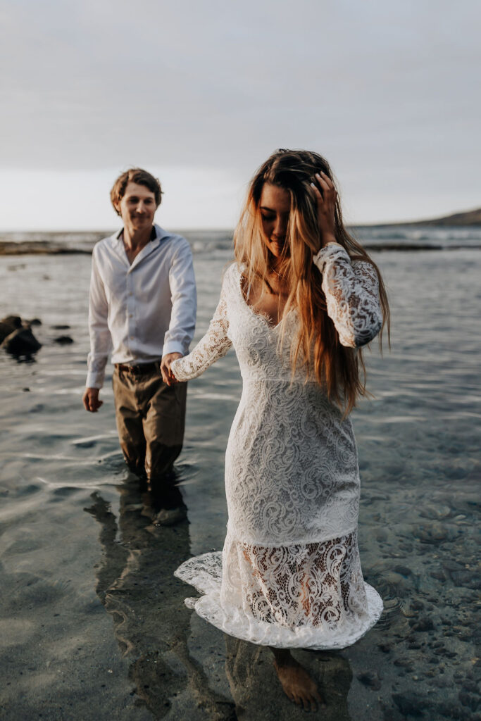 Big Island elopement photographer captures bride walking into water holding groom's hand