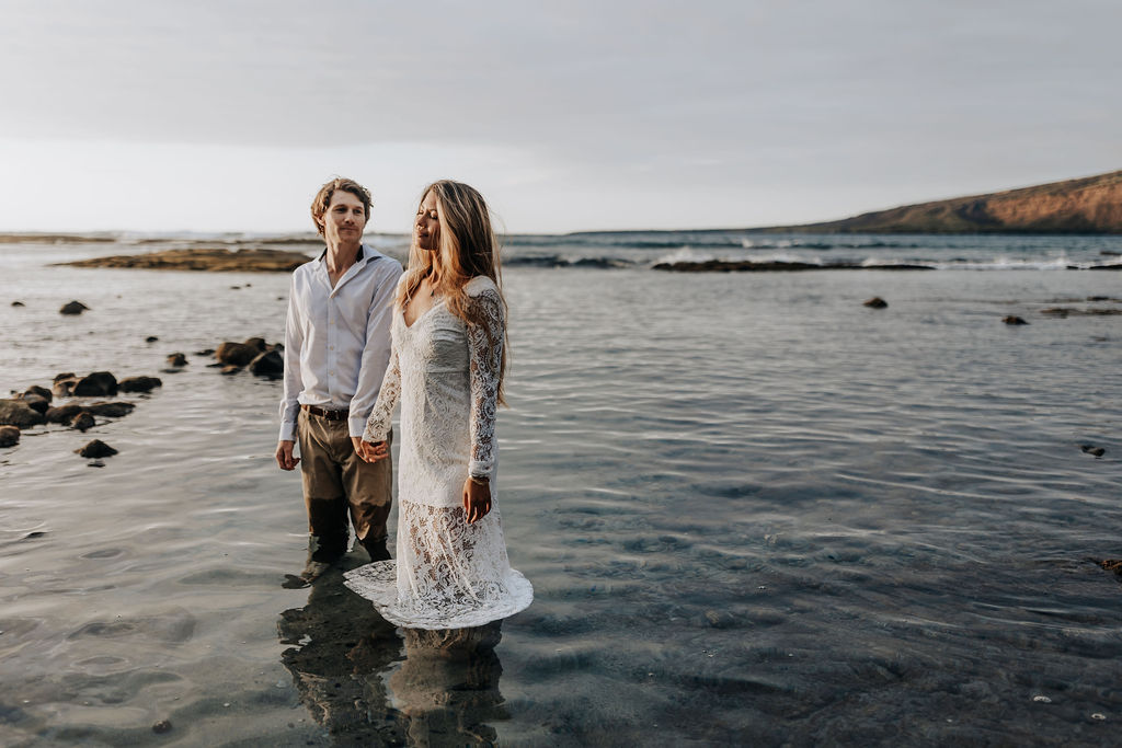 Big Island elopement photographer captures bride and groom in water holding hands after dreamy Big Island elopement