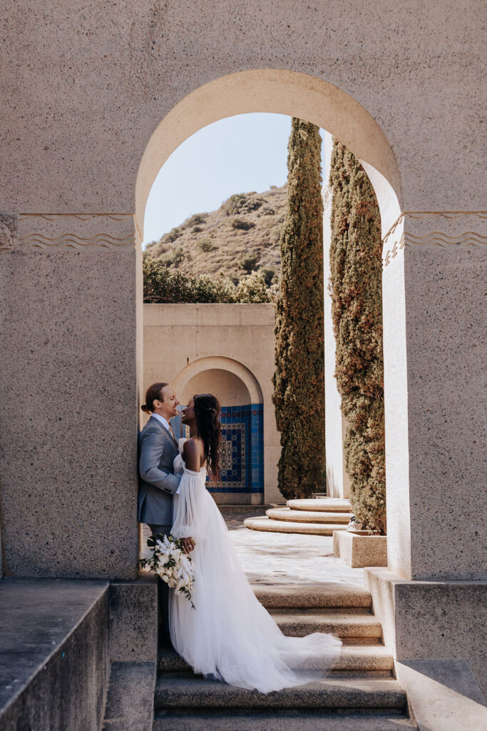 Destination elopement photographer captures couple leaning against arch 