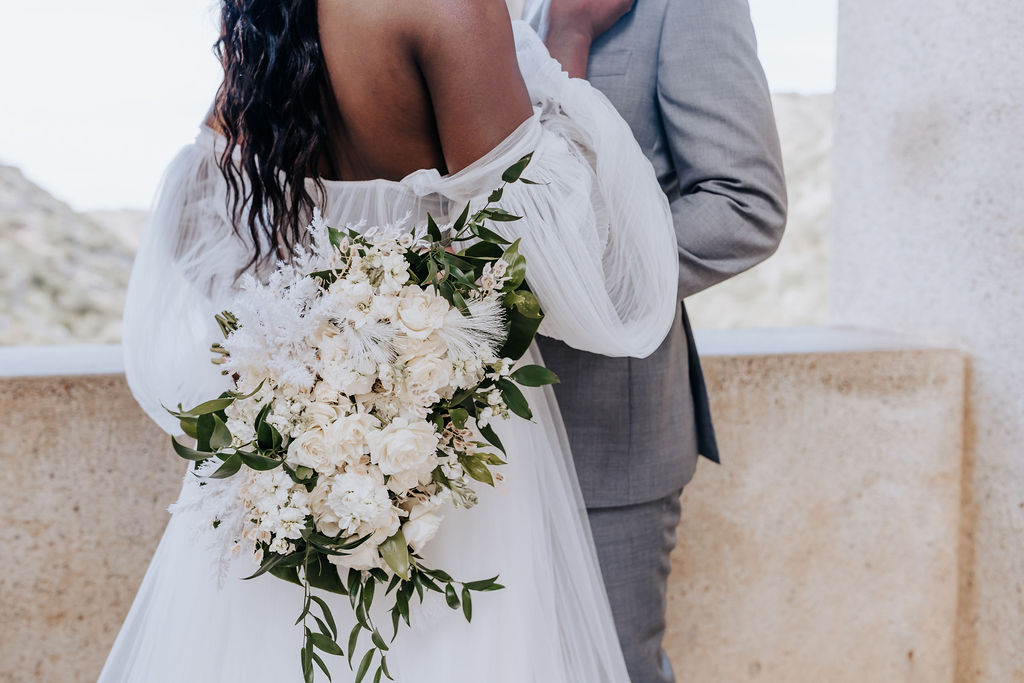 Destination elopement photographer captures bride and groom hugging with bridal bouquet behind back