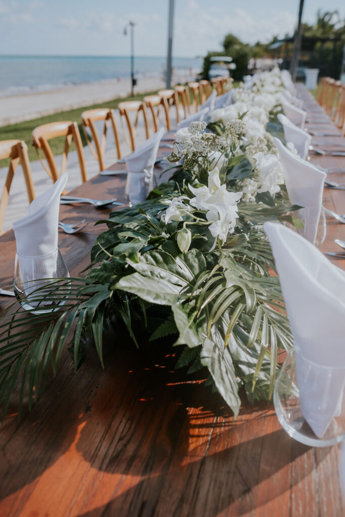 Destination wedding photographer captures wedding reception table covered with palm fronds and other decor for destination resort wedding reception