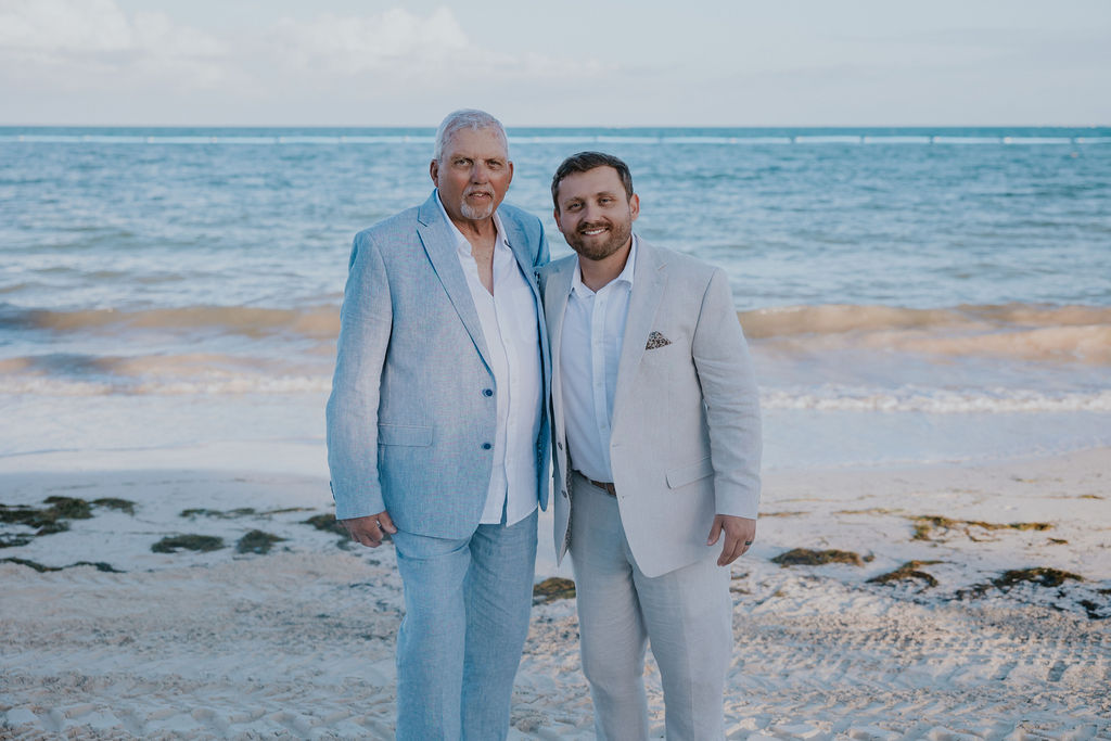 Destination wedding photographer captures groom standing with father on beach during destination resort wedding bridal portraits
