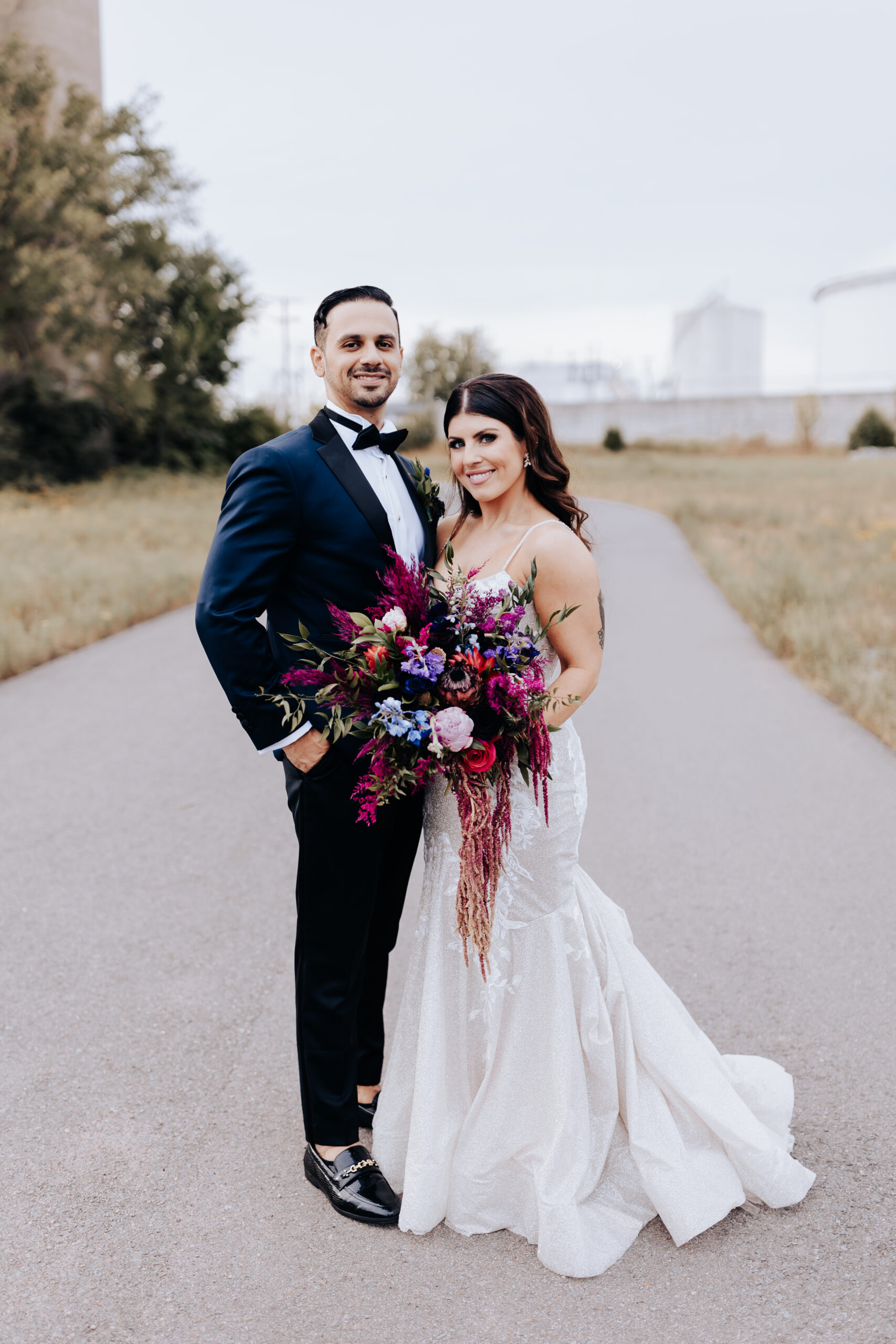 Destination Elopement Photographers capture bride and groom embracing while bride holds vibrant and moody bridal bouquet