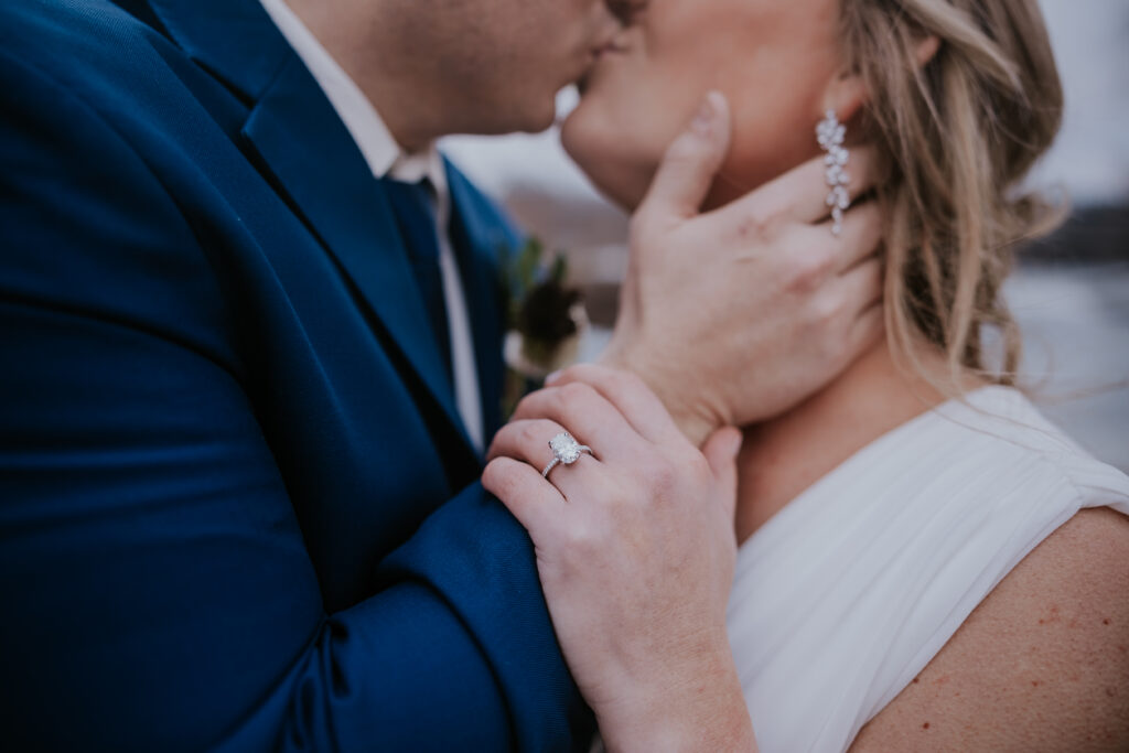 Destination elopement photographer captures close up of bride and groom kiss with bride placing hand on groom's arm
