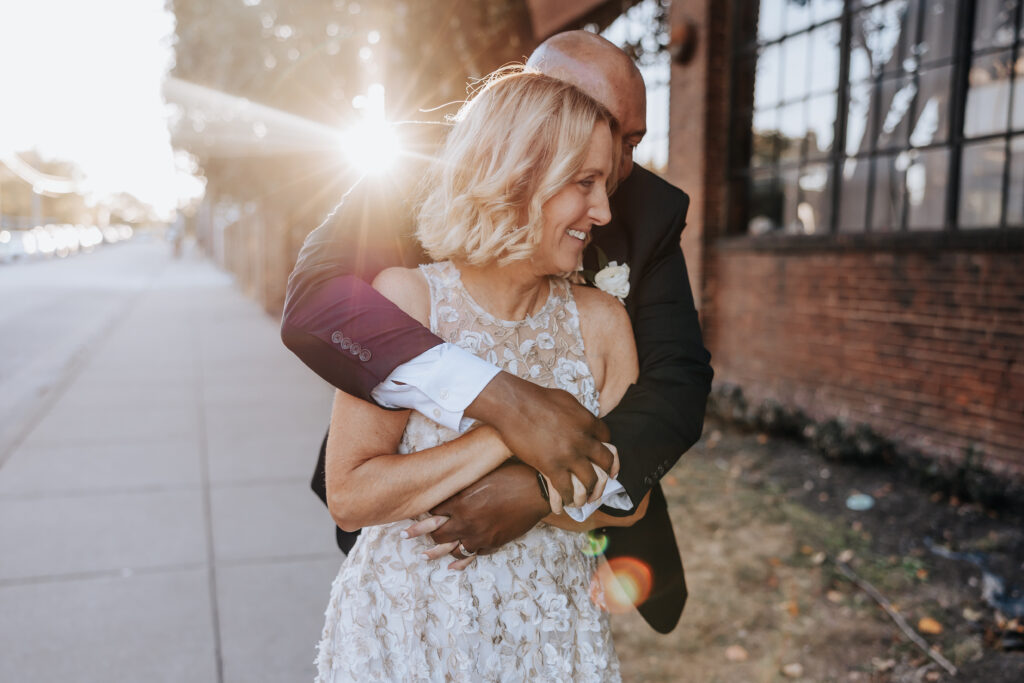 Destination elopement photographer captures groom holding bride from behind and laughing during golden hour bridal portraits
