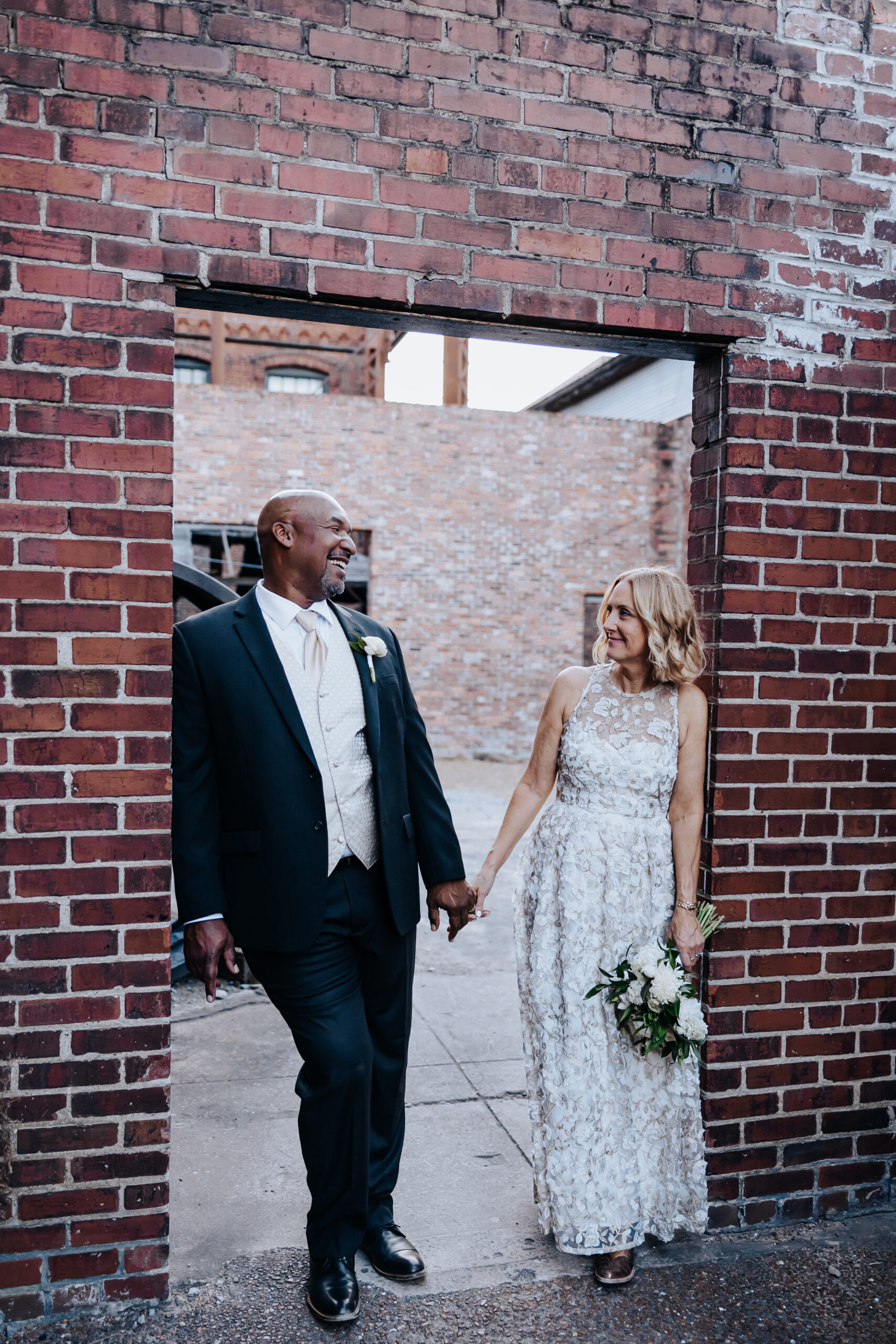 Destination elopement photographer captures bride and groom leaning against brick door holding hands
