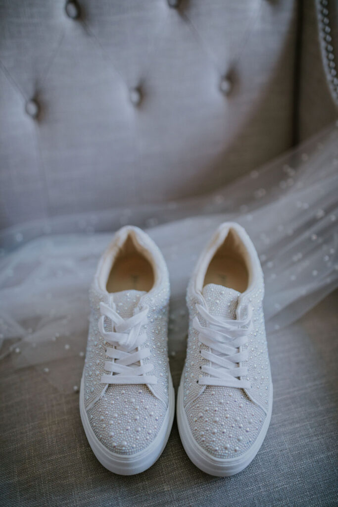 Destination wedding photographer captures bride's shoes sitting on chair with veil behind