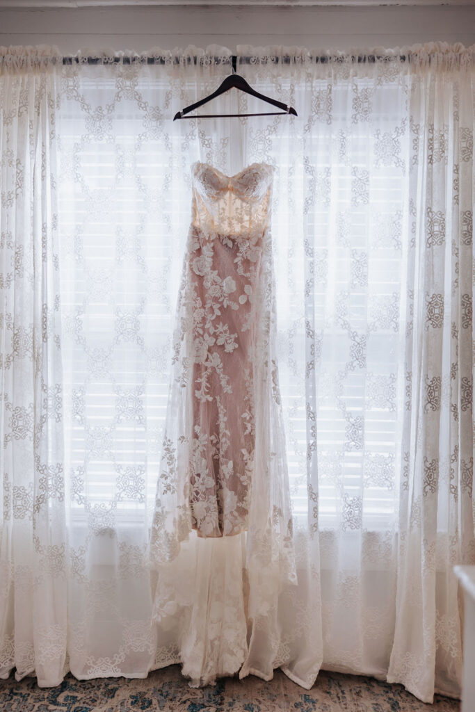 Destination wedding photographer captures wedding dress hanging from window