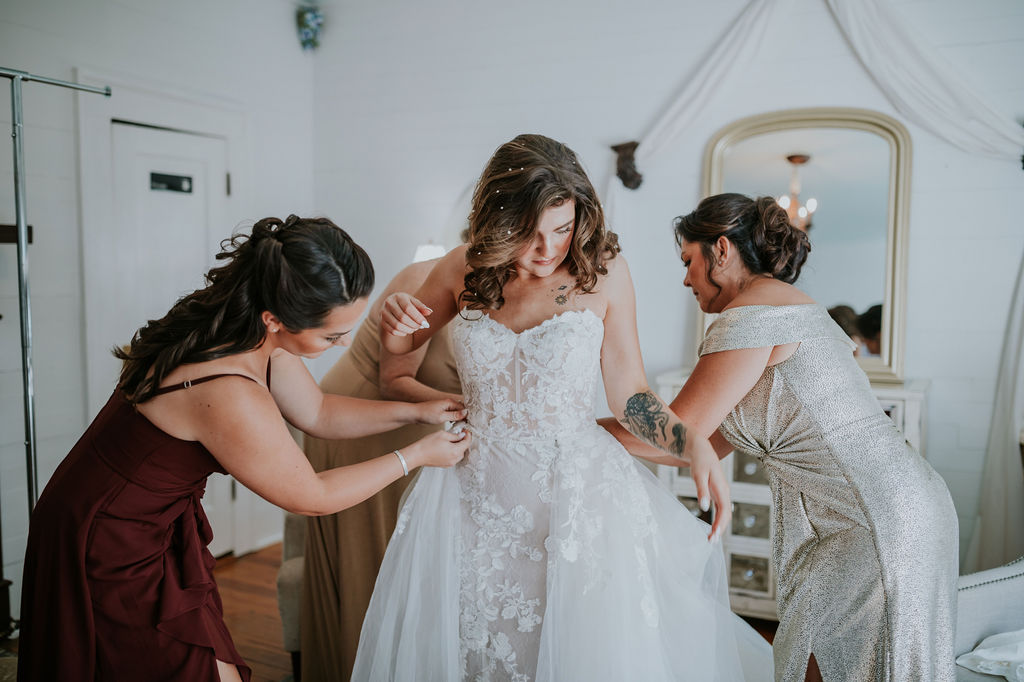 Destination wedding photographer captures bride in wedding dress with help from bridesmaids and mother