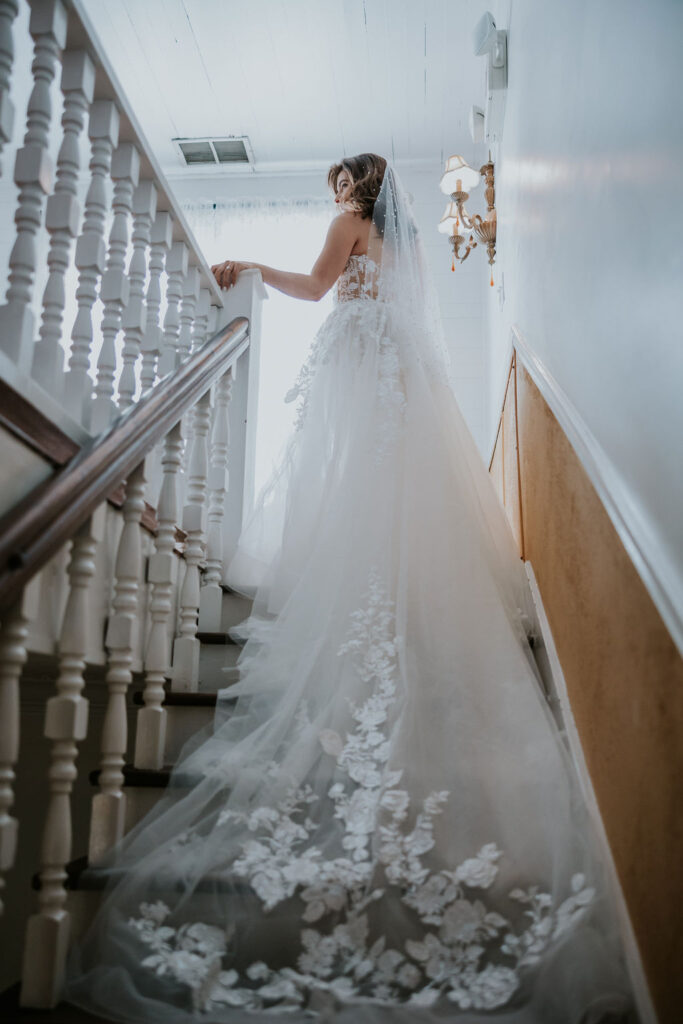 Destination wedding photographer captures bride walking upstairs wearing wedding dress and veil
