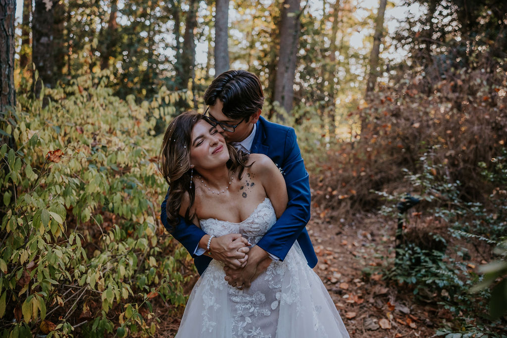 Destination Wedding Photographer captures bride and groom hugging in forest 