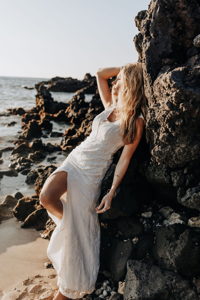 Destination wedding photographer captures bride leaning against rock after Hawaii beach wedding