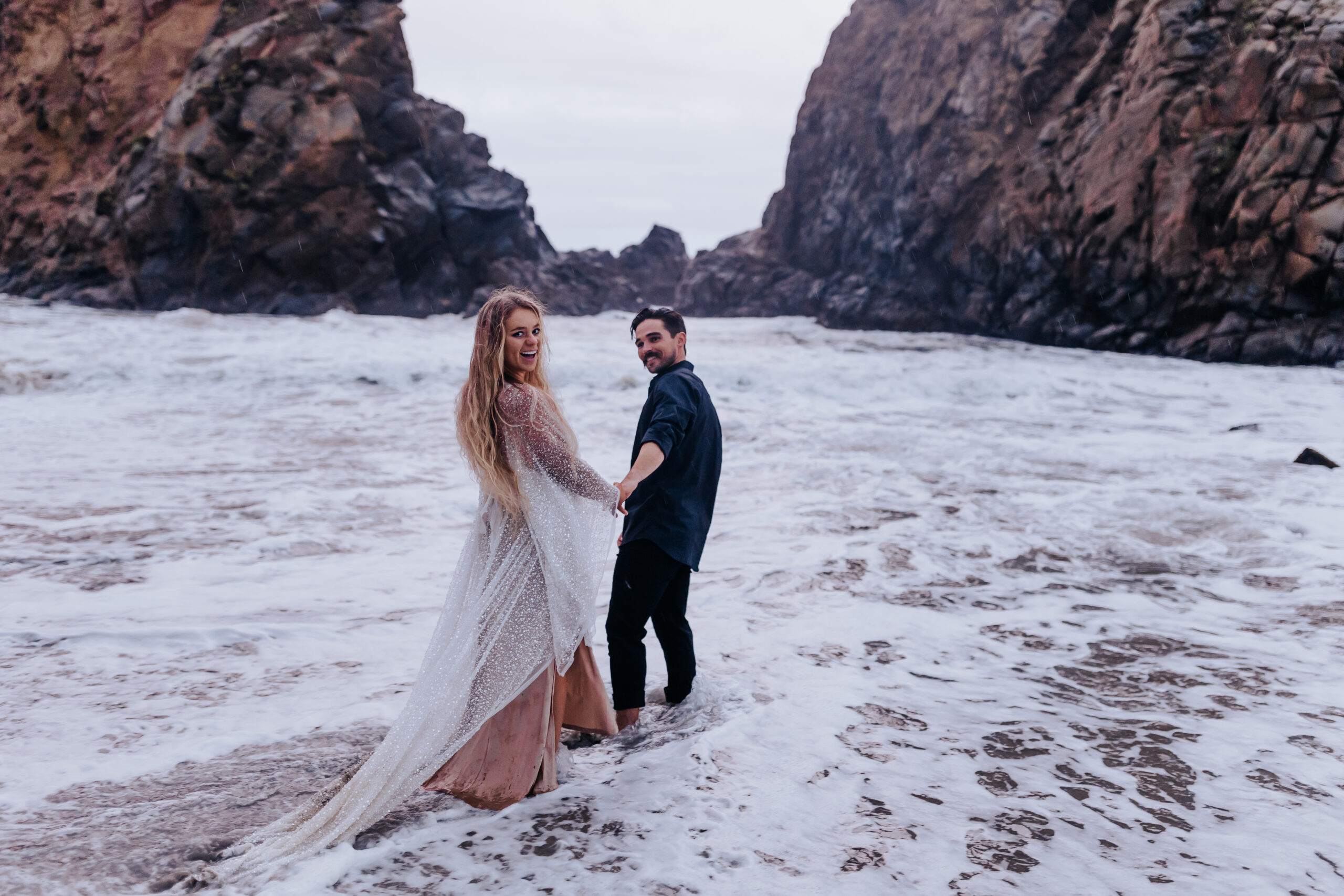 Destination Wedding Photographer captures bride and groom walking into ocean after destination wedding in Oregon