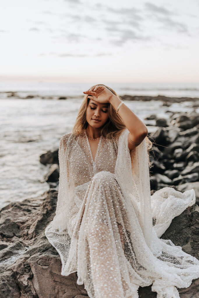 Destination wedding photographer captures bride sitting on rock after Hawaii beach wedding