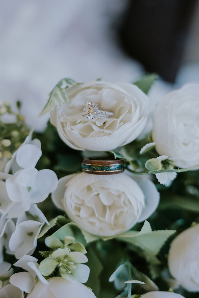 Destination wedding photographer captures white flowers with wedding rings in them