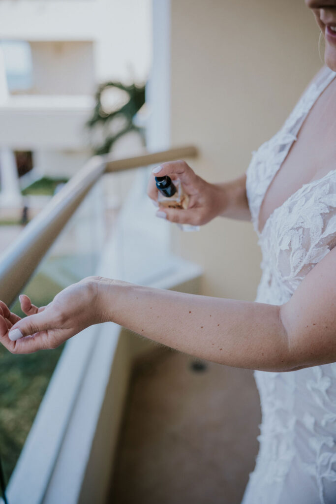 Destination wedding photographer captures bride putting perfume on wrist