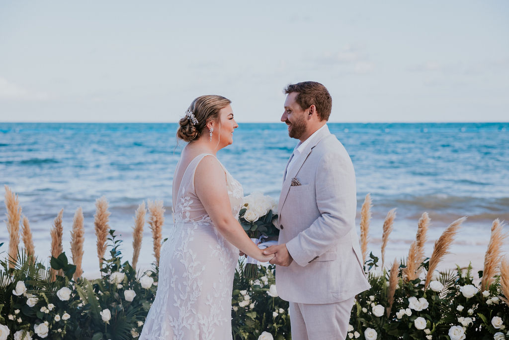 Destination wedding photographer captures couple holding hands during beachside ceremony