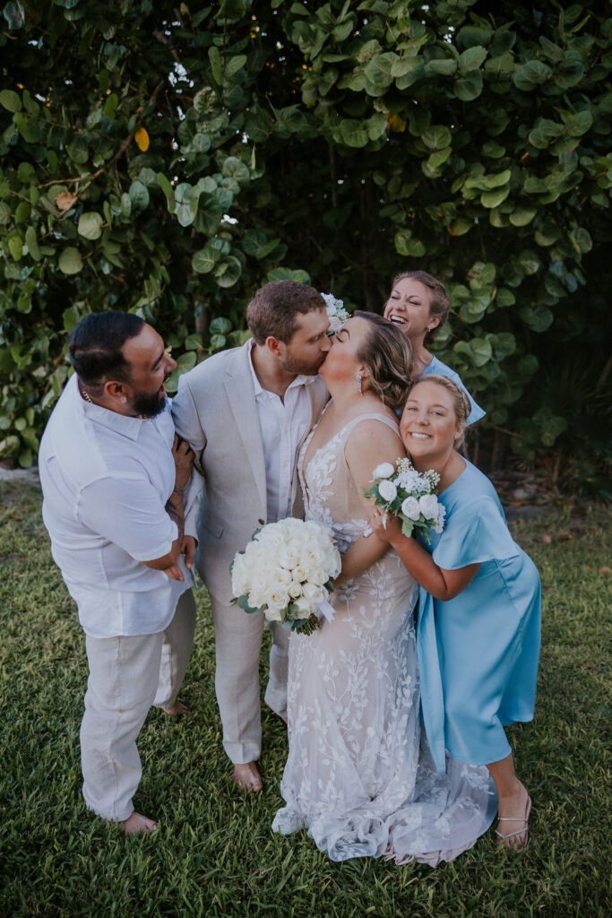 Destination wedding photographer captures couple kissing while wedding party surrounds them