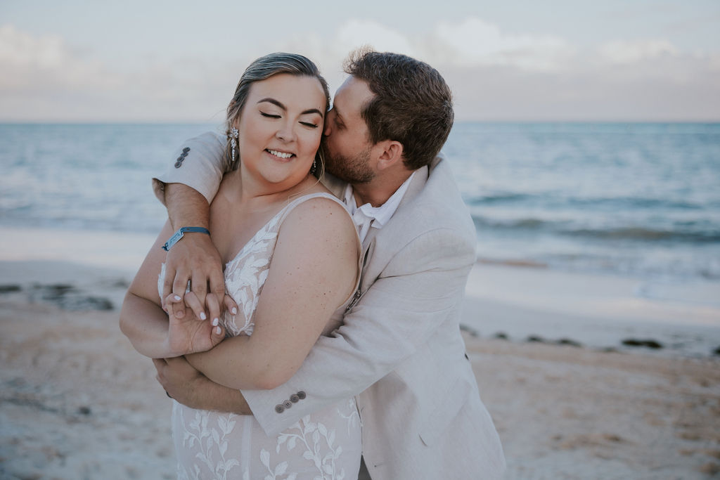 Destination wedding photographer captures groom kissing bride and hugging her