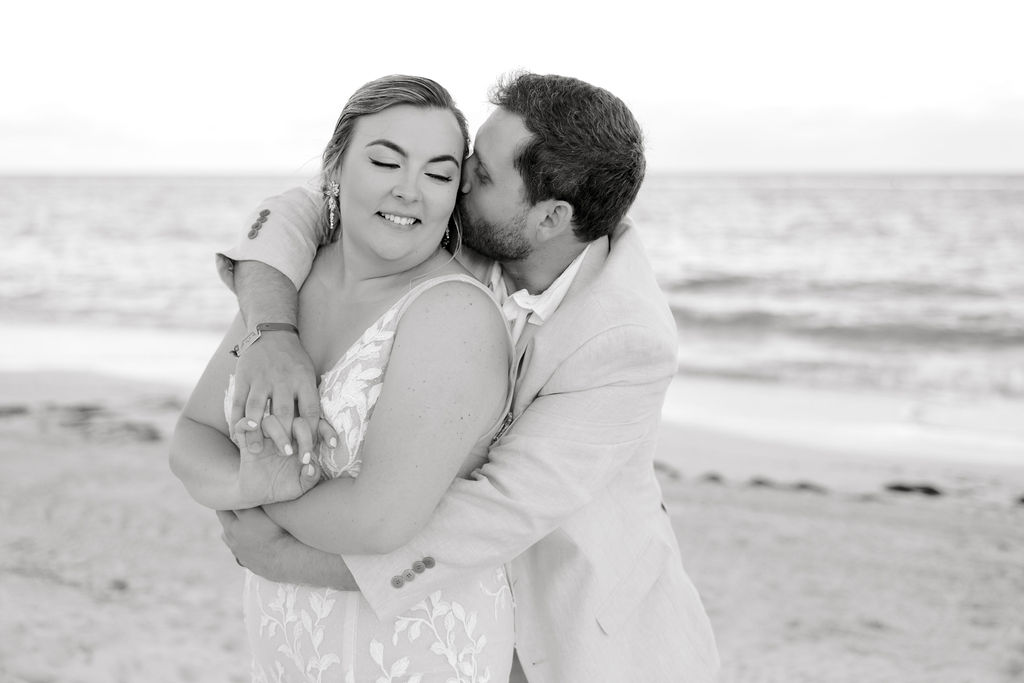 Destination wedding photographer captures groom hugging bride and kissing her