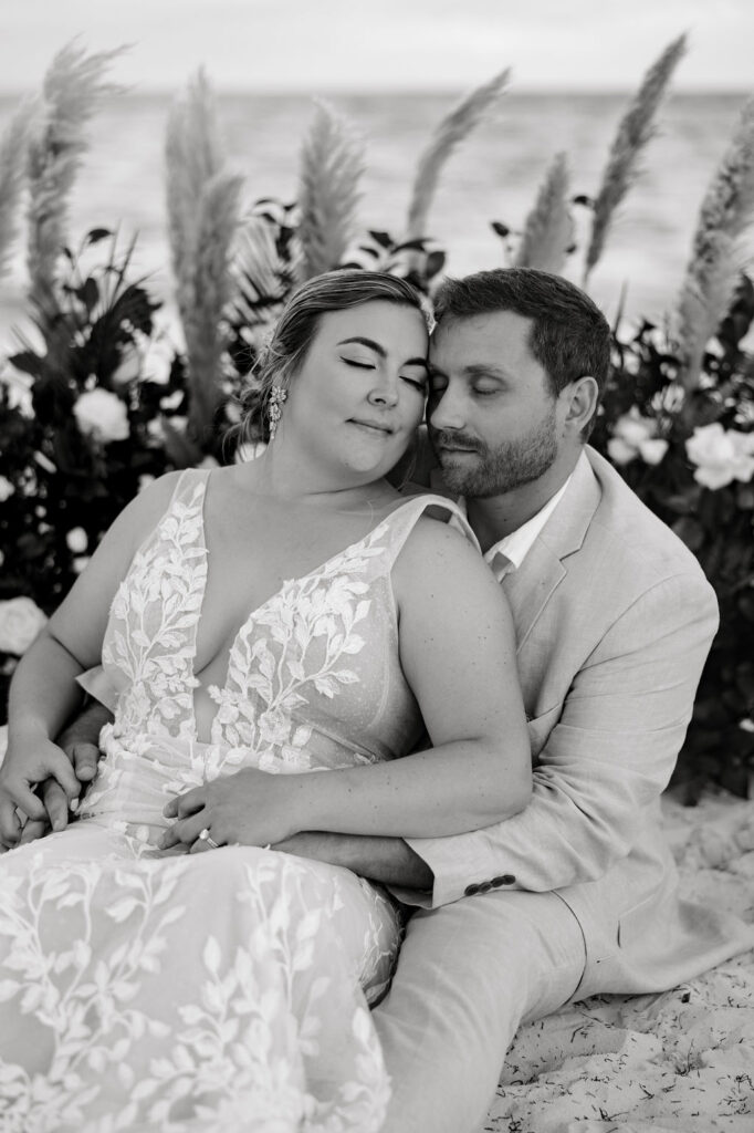 Destination wedding photographer captures bride and groom sitting together in sand
