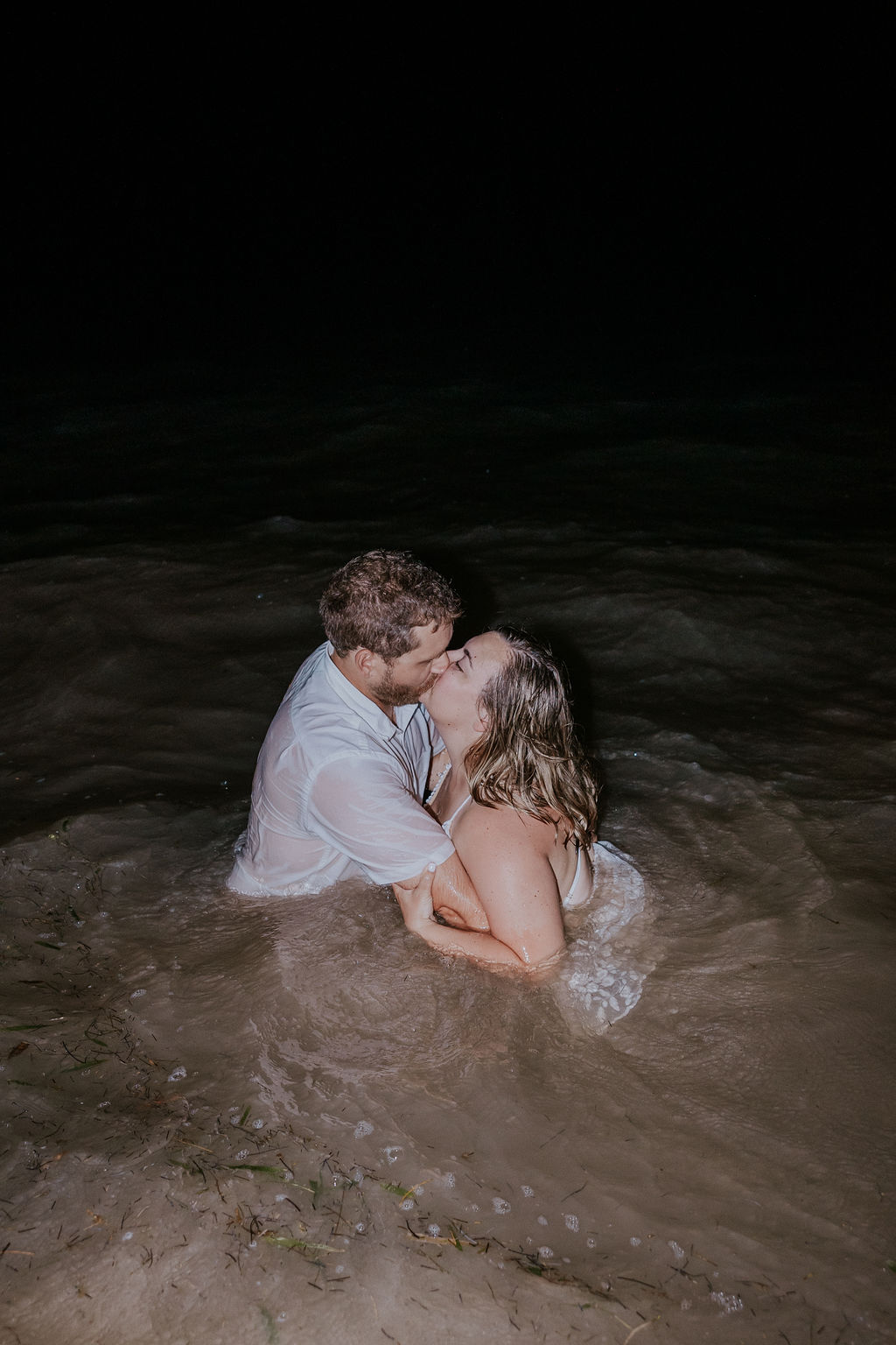 Destination Wedding Photographer captures bride and groom kissing in water