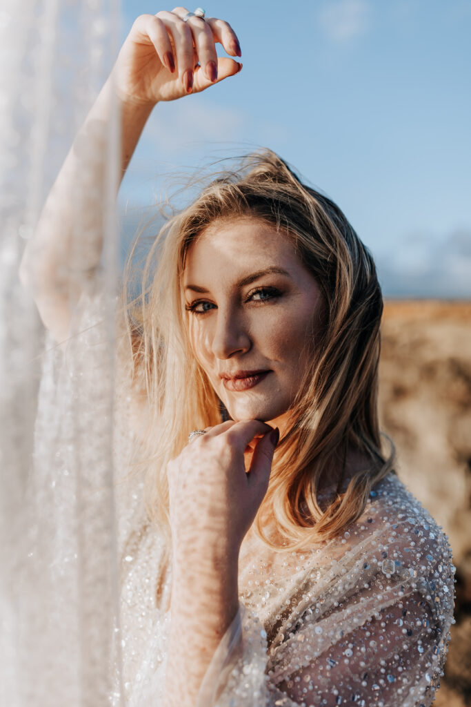 Destination Wedding Photographer captures bride holding up veil in sunlight