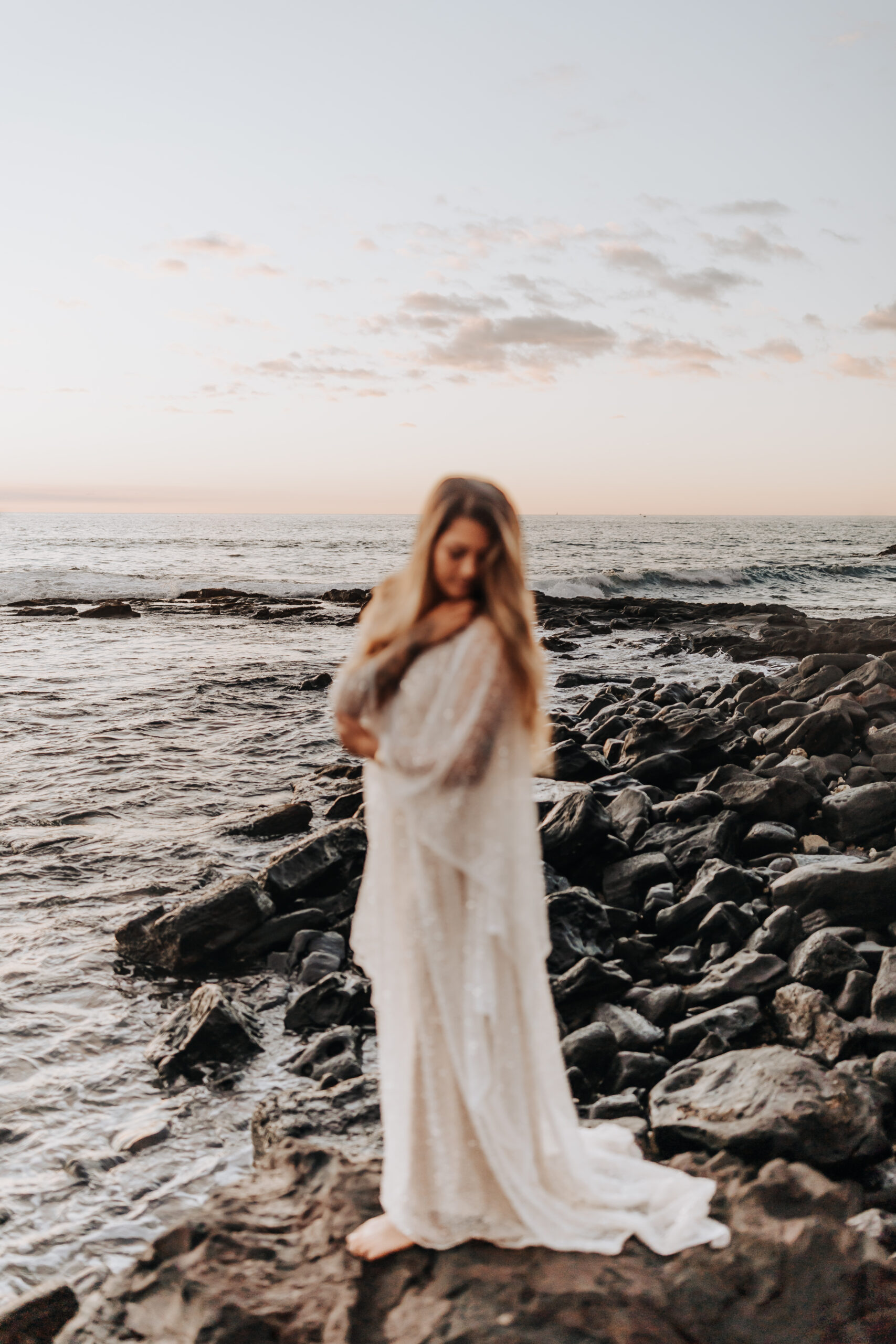 Destination Wedding Photographer captures bride wearing long dress in rocks