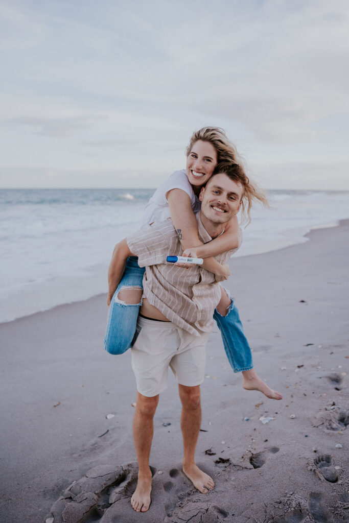 Destination Wedding Photographer captures woman on man's back during Indian Harbour maternity photos