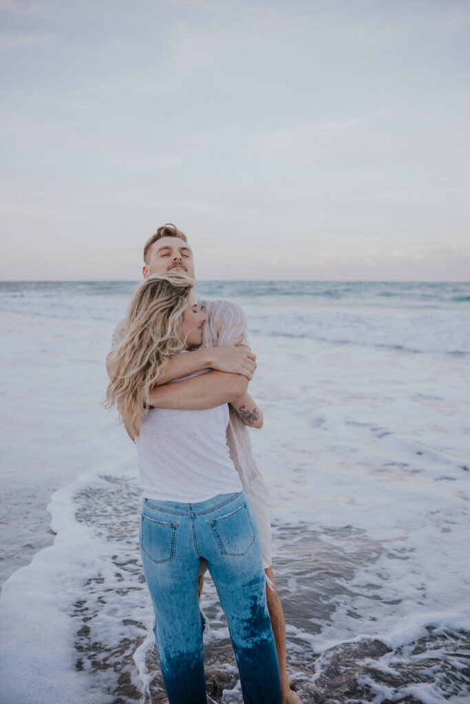 Destination Elopement Photographers capture man and woman hugging in ocean during outdoor engagements