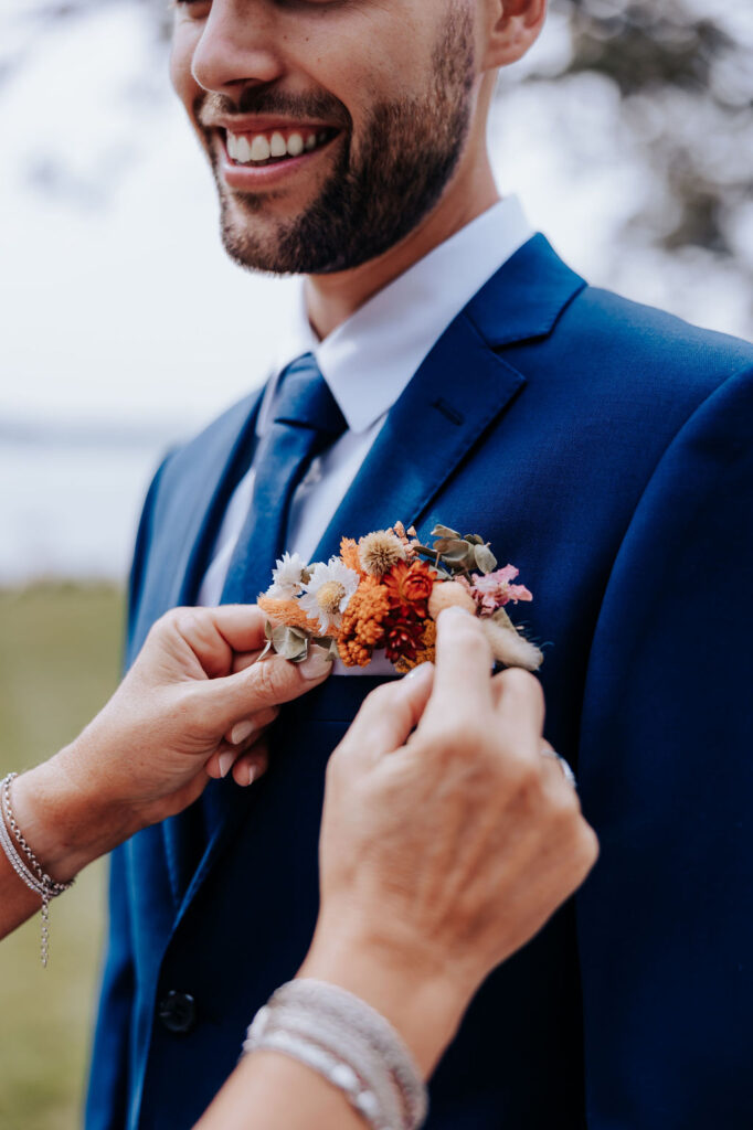 Destination wedding photographer captures mother helping groom with boutainniere