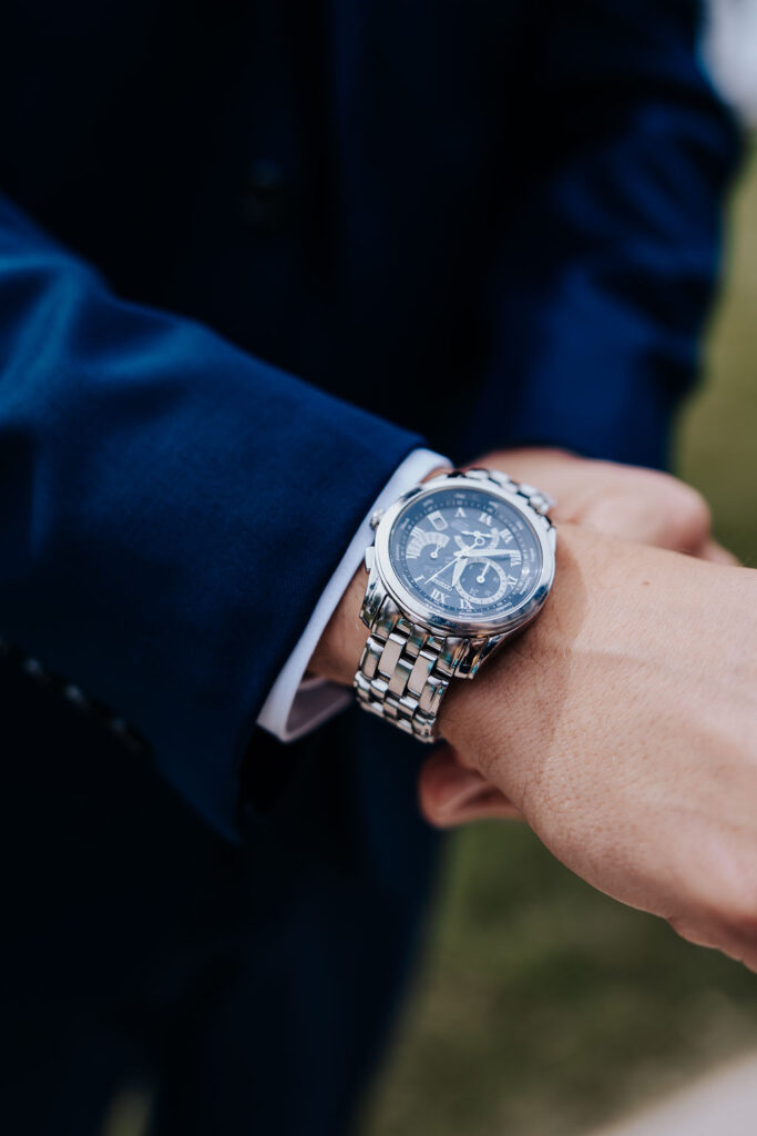 Destination wedding photographer captures groom adjusting watch 