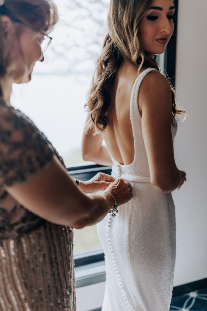 Destination wedding photographer captures mother buttoning bride's wedding dress